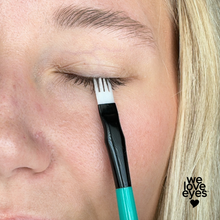 Load image into Gallery viewer, Person using a fork to groom eyelashes with 'we love eyes' branding.