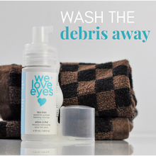 Load image into Gallery viewer, Eye makeup remover bottle with text 'Wash the debris away' and a checkered towel in the background.