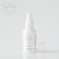 White spray bottle labeled 'we love eyes' on a light gray background