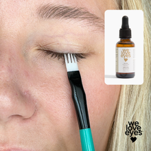 Load image into Gallery viewer, Person applying eyelash serum with a brush, inset showing 'we love eyes' product.
